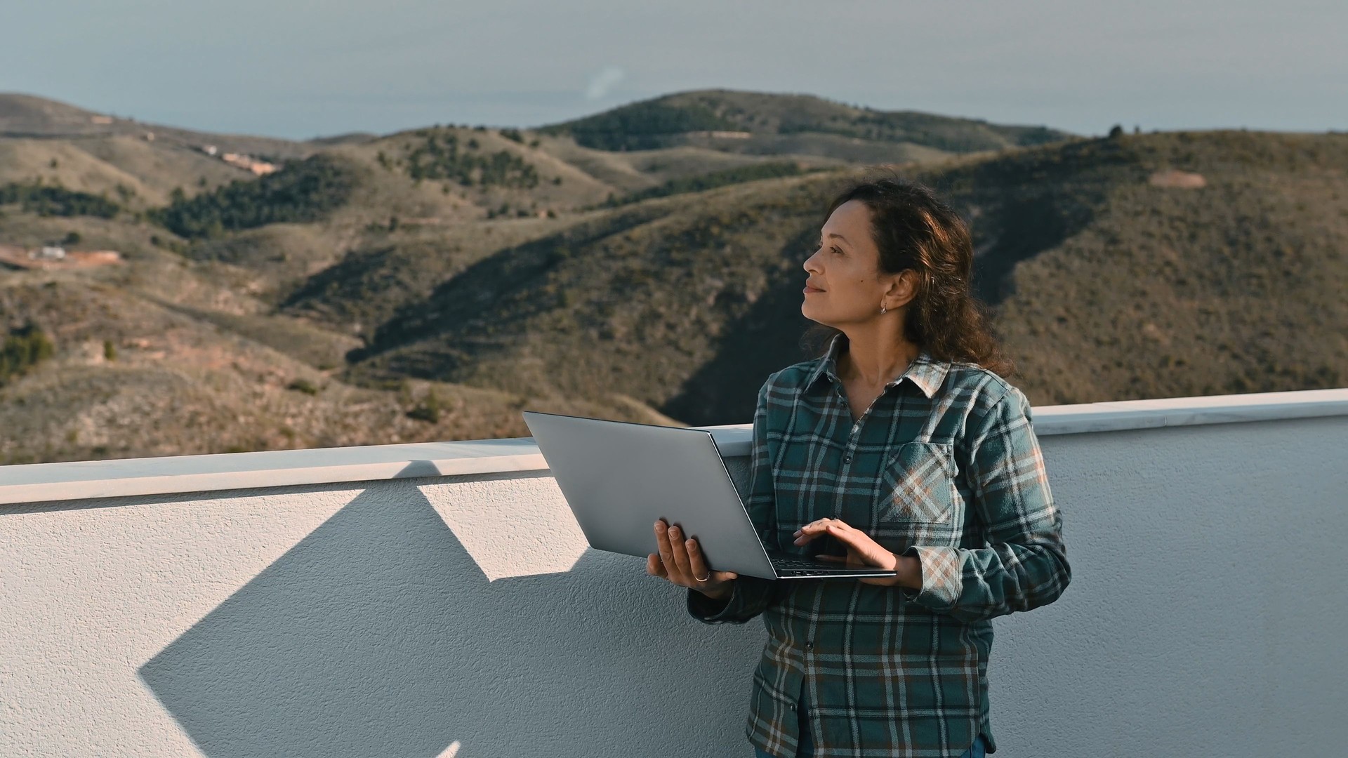 Remote Worker on Terrace Overlooking a Serene Mountain Landscape